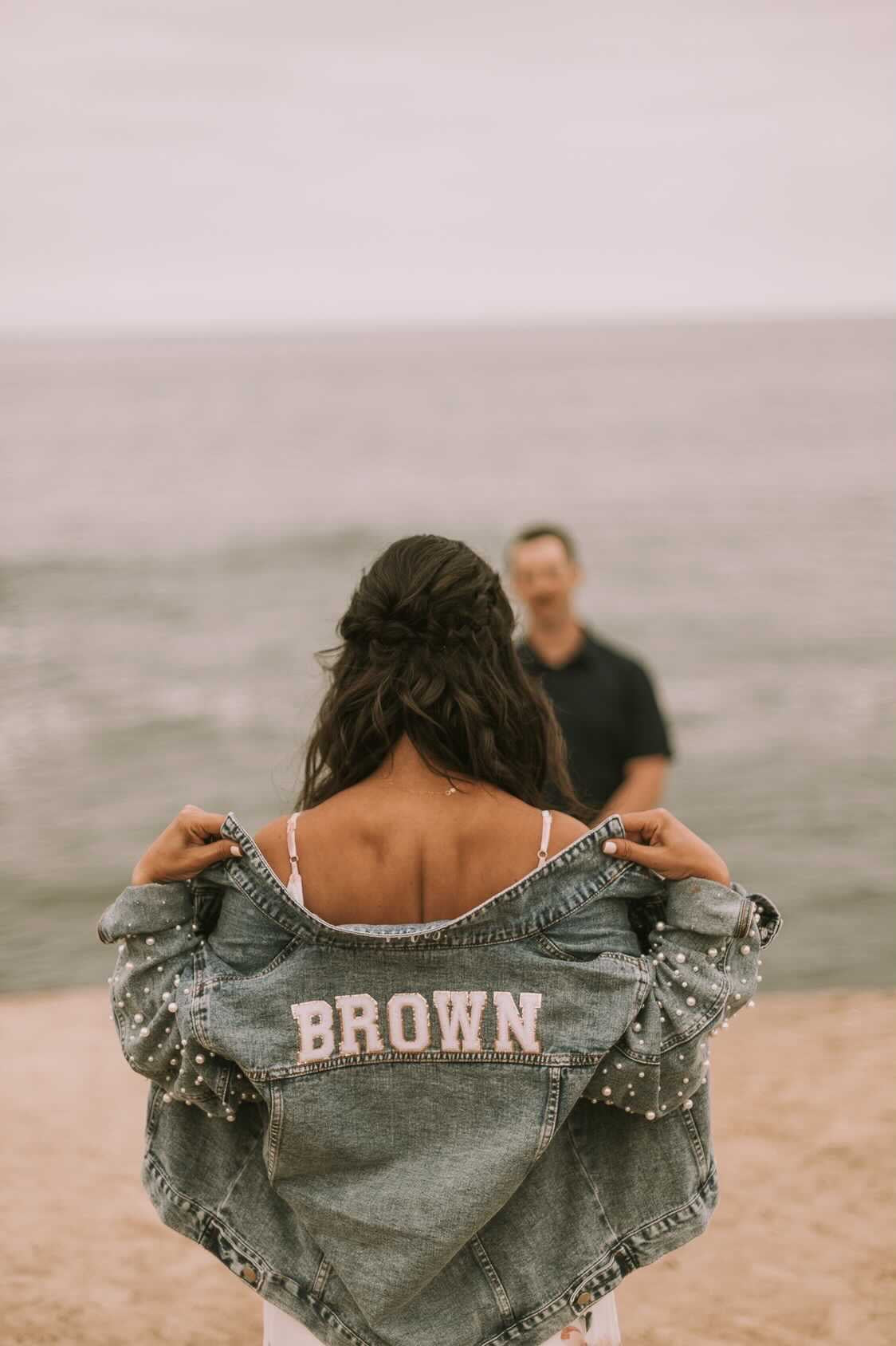 Blue denim jacket with pearls on sleeves and future last name with patches on back.