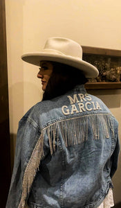 Bride wearing jacket with future last name on blue denim rhinestone fringe jacket.